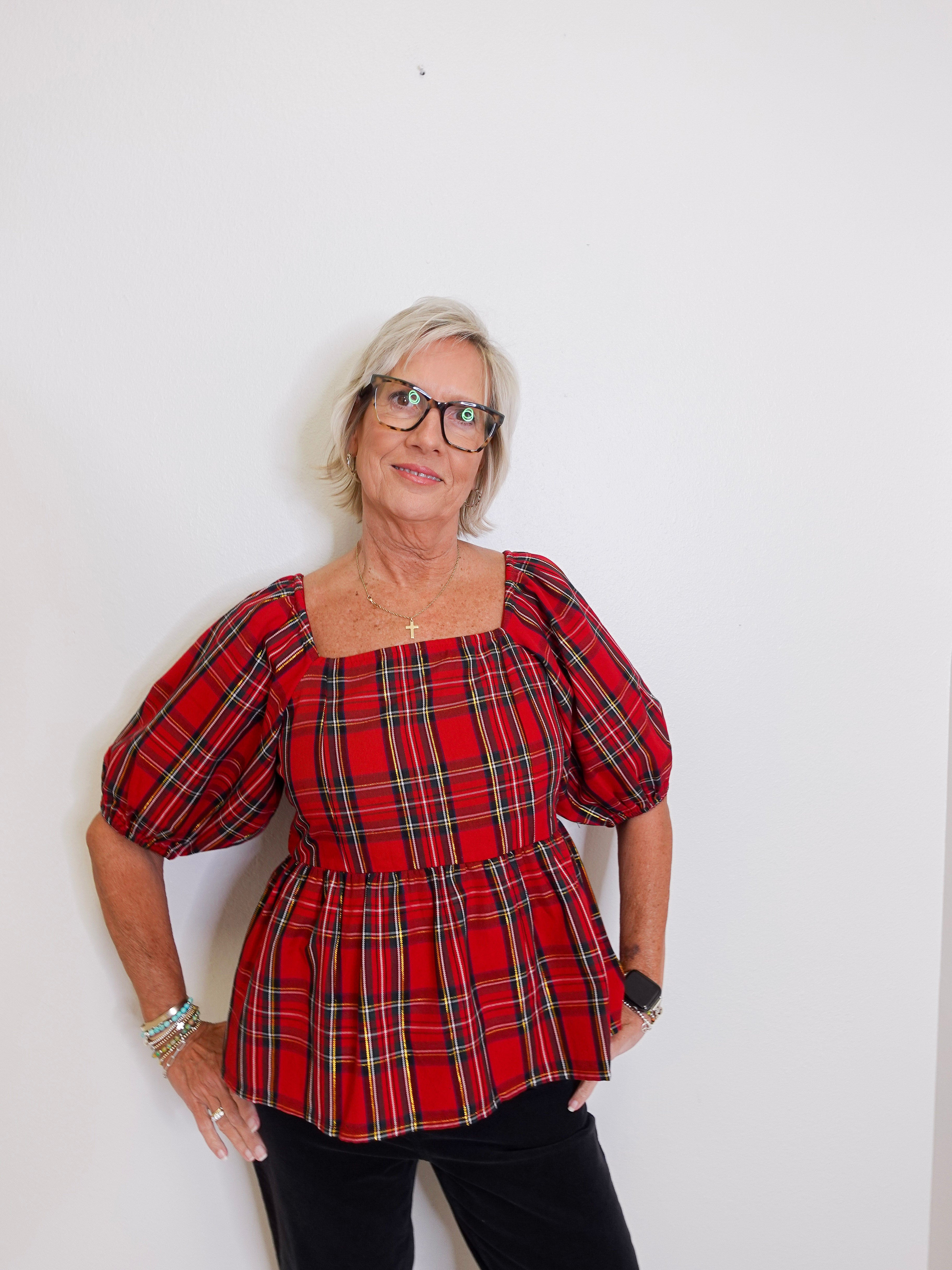 woman wearing a plaid blouse against a white background. 
