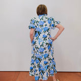 Woman wearing a floral dress with blue flowers against a plain background