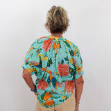 Person wearing a colorful floral blouse with a plain background