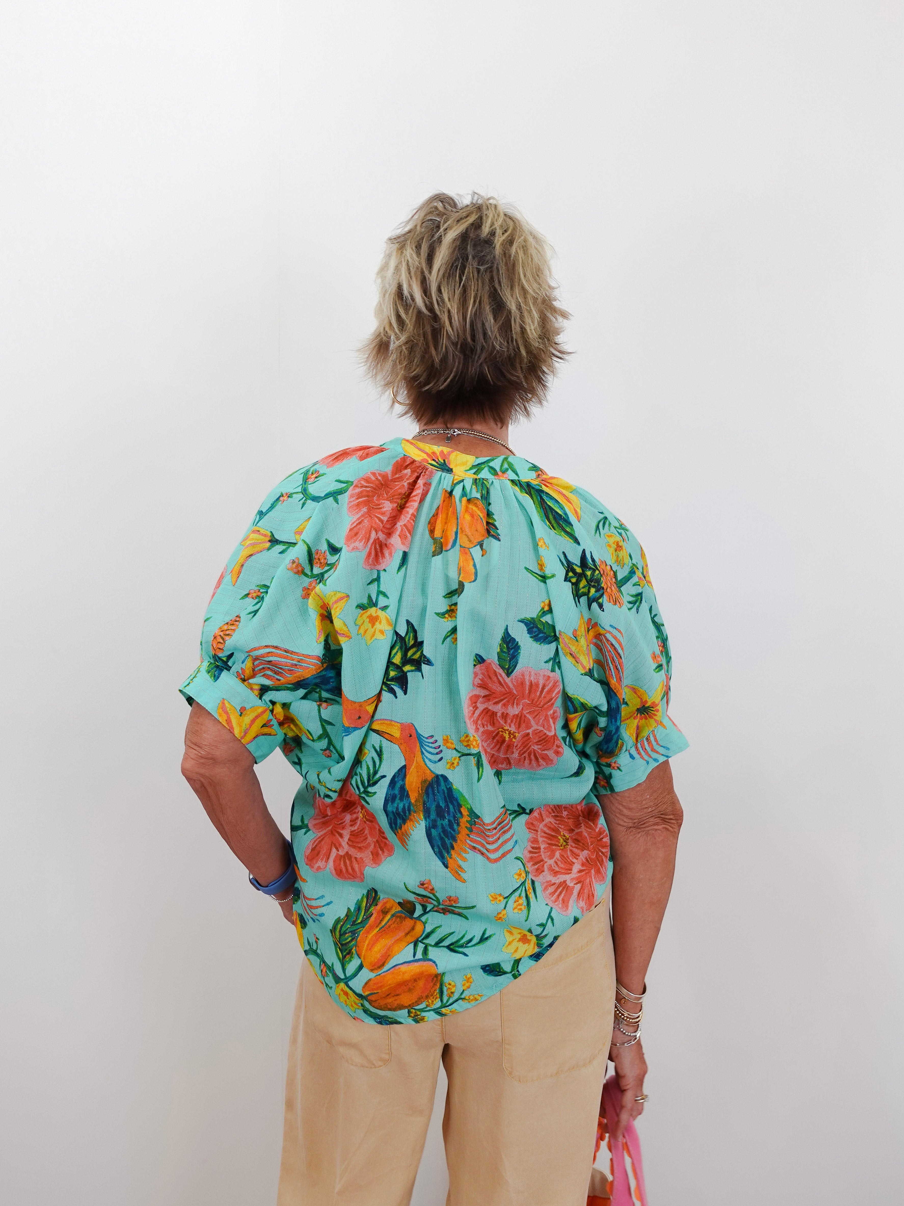 Person wearing a colorful floral blouse with a plain background