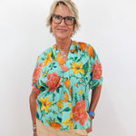 Woman wearing a colorful floral blouse against a white background