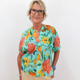 Woman wearing a colorful floral blouse against a white background