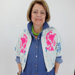 Woman wearing a blue outfit with a floral patterned cardigan against a white background
