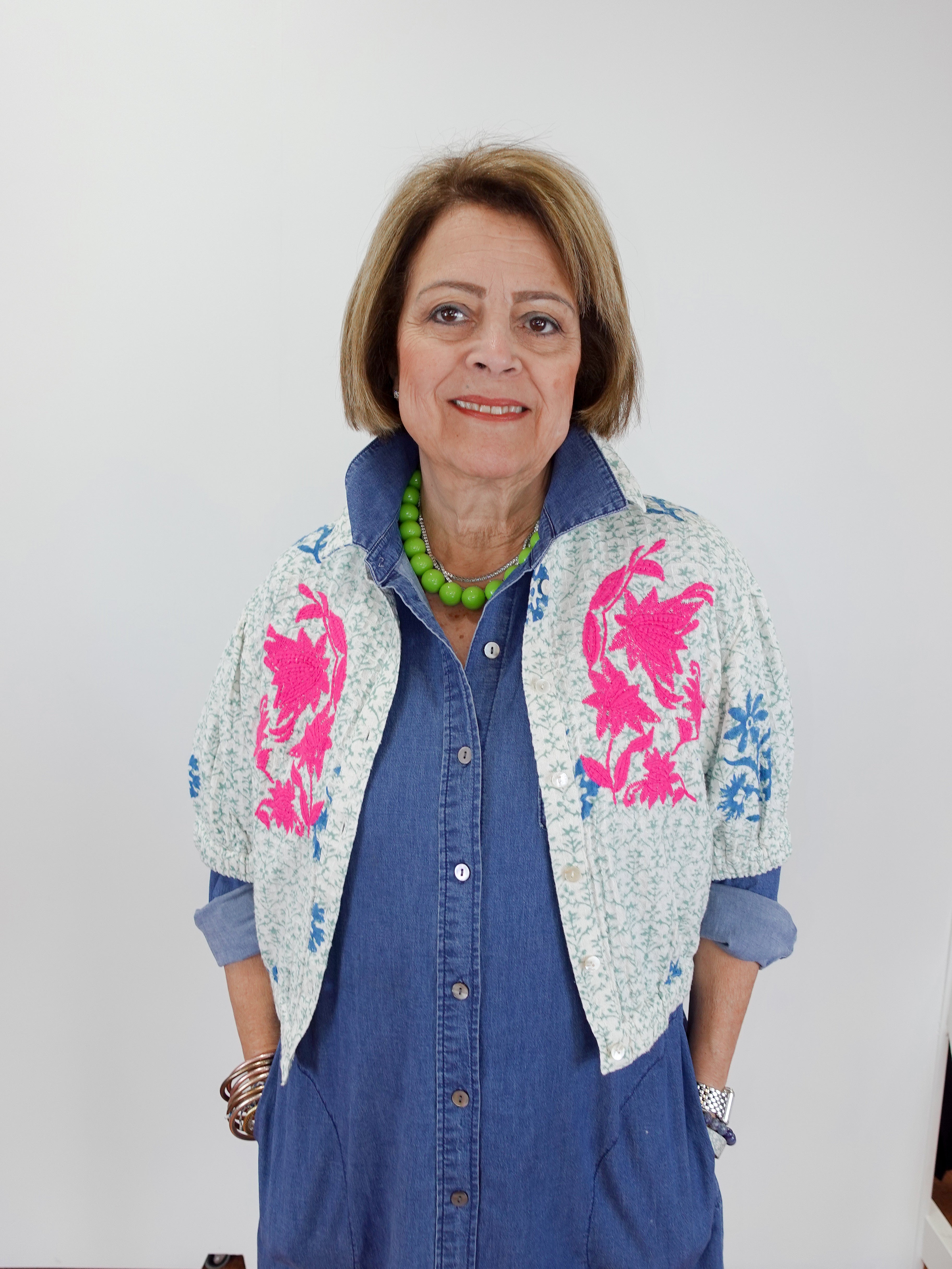 Woman wearing a blue outfit with a floral patterned cardigan against a white background