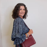 Woman holding a red handbag against a white background