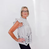 Woman wearing a floral blouse and glasses against a white background