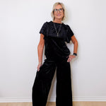 Person wearing a black outfit against a white wall