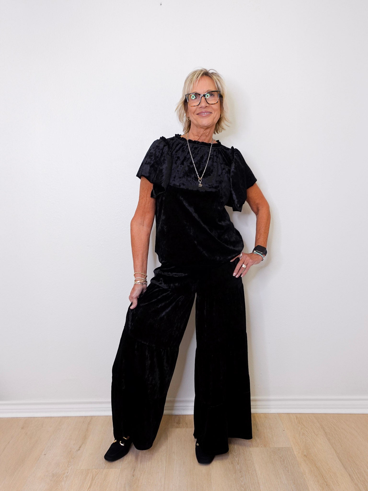 Person wearing a black outfit against a white wall