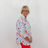 Person wearing a colorful patterned shirt and red pants against a white background