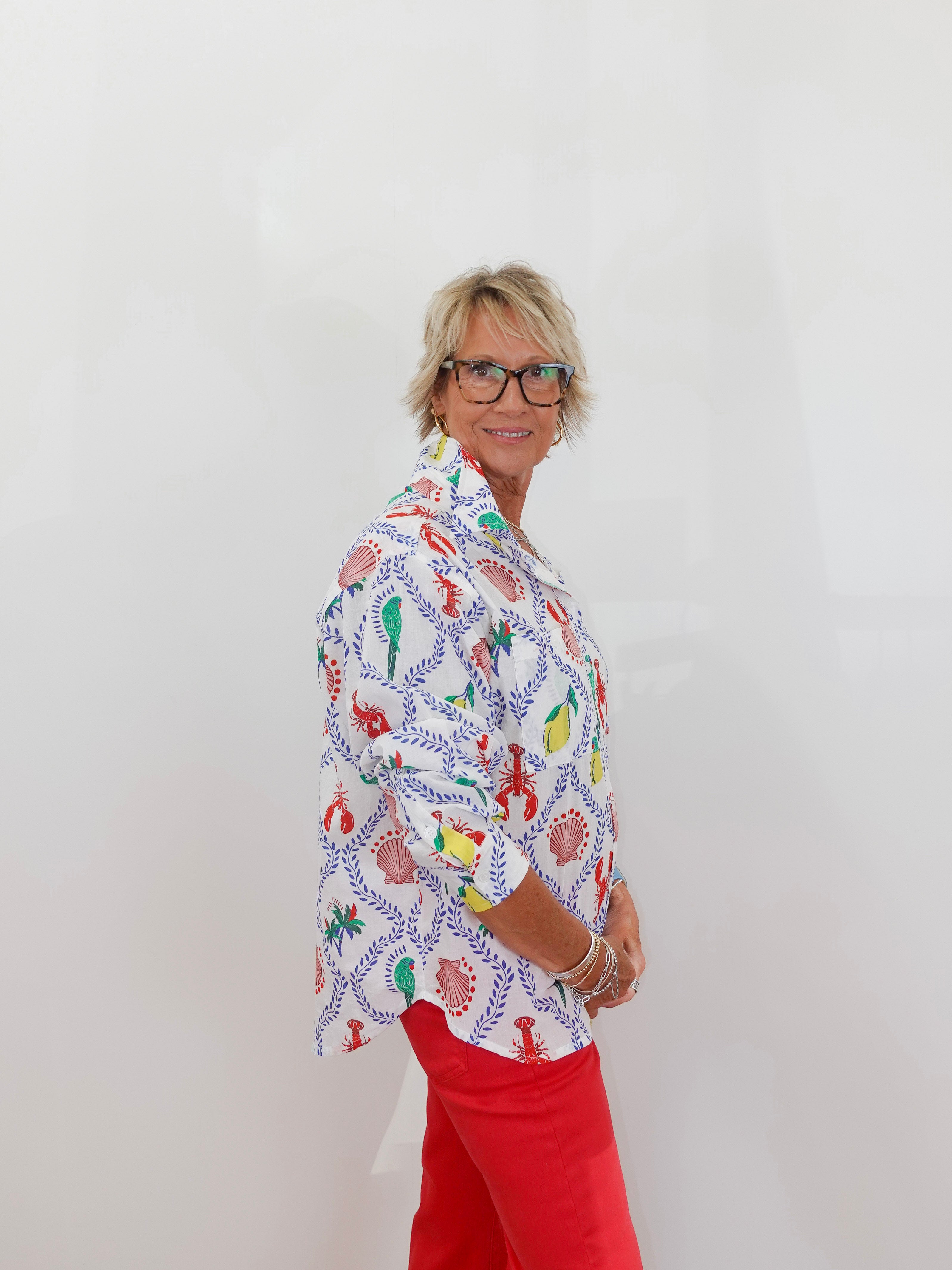 Person wearing a colorful patterned shirt and red pants against a white background