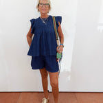 Woman wearing a blue outfit with a white wall background
