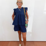 Woman wearing a blue outfit with a white wall background
