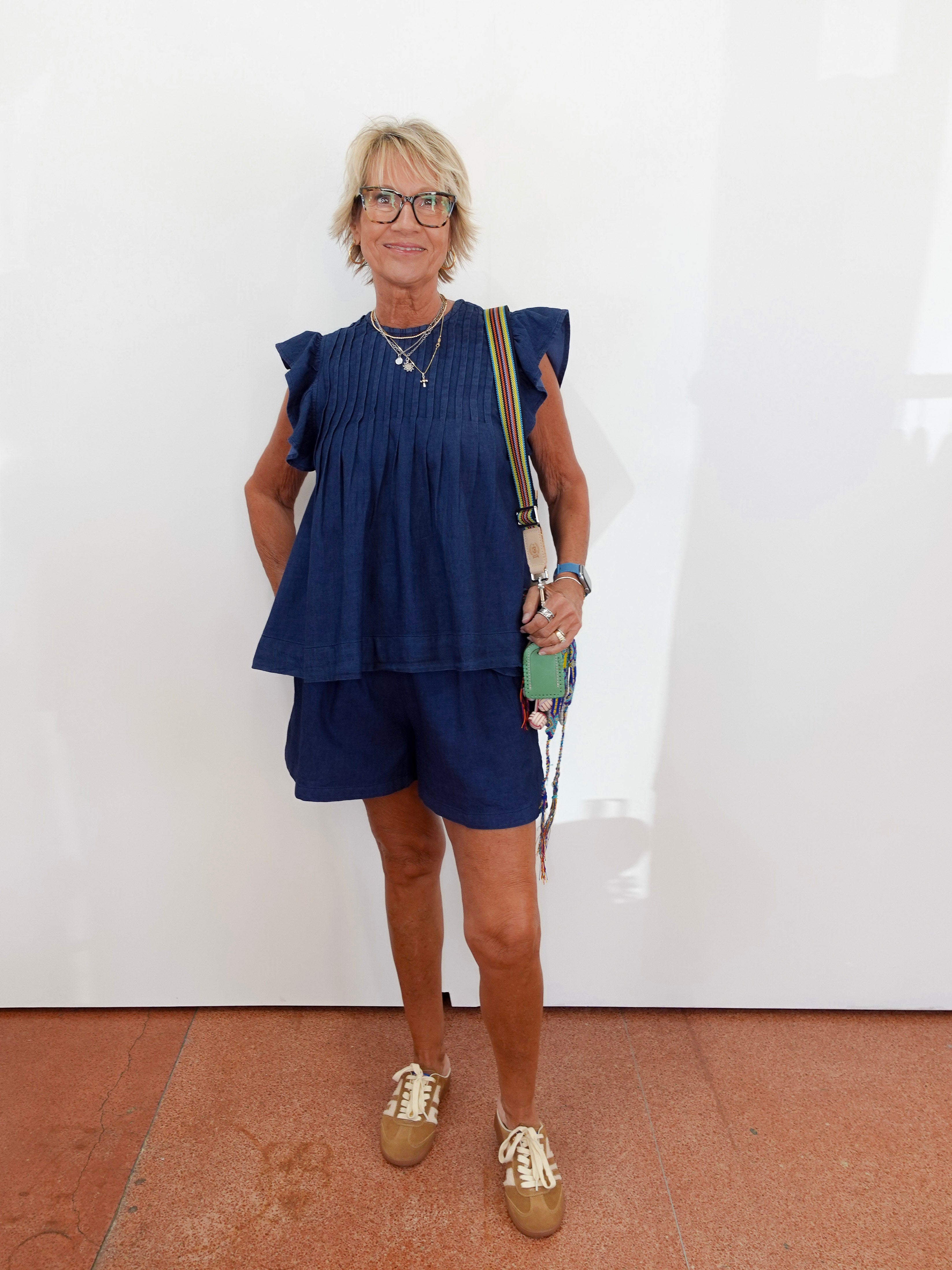 Woman wearing a blue outfit with a white wall background