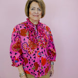 Woman wearing a colorful patterned blouse against a pink background