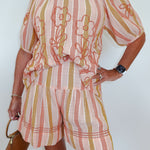 Person wearing a pink and yellow striped outfit with floral embroidery on a white background
