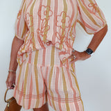 Person wearing a pink and yellow striped outfit with floral embroidery on a white background