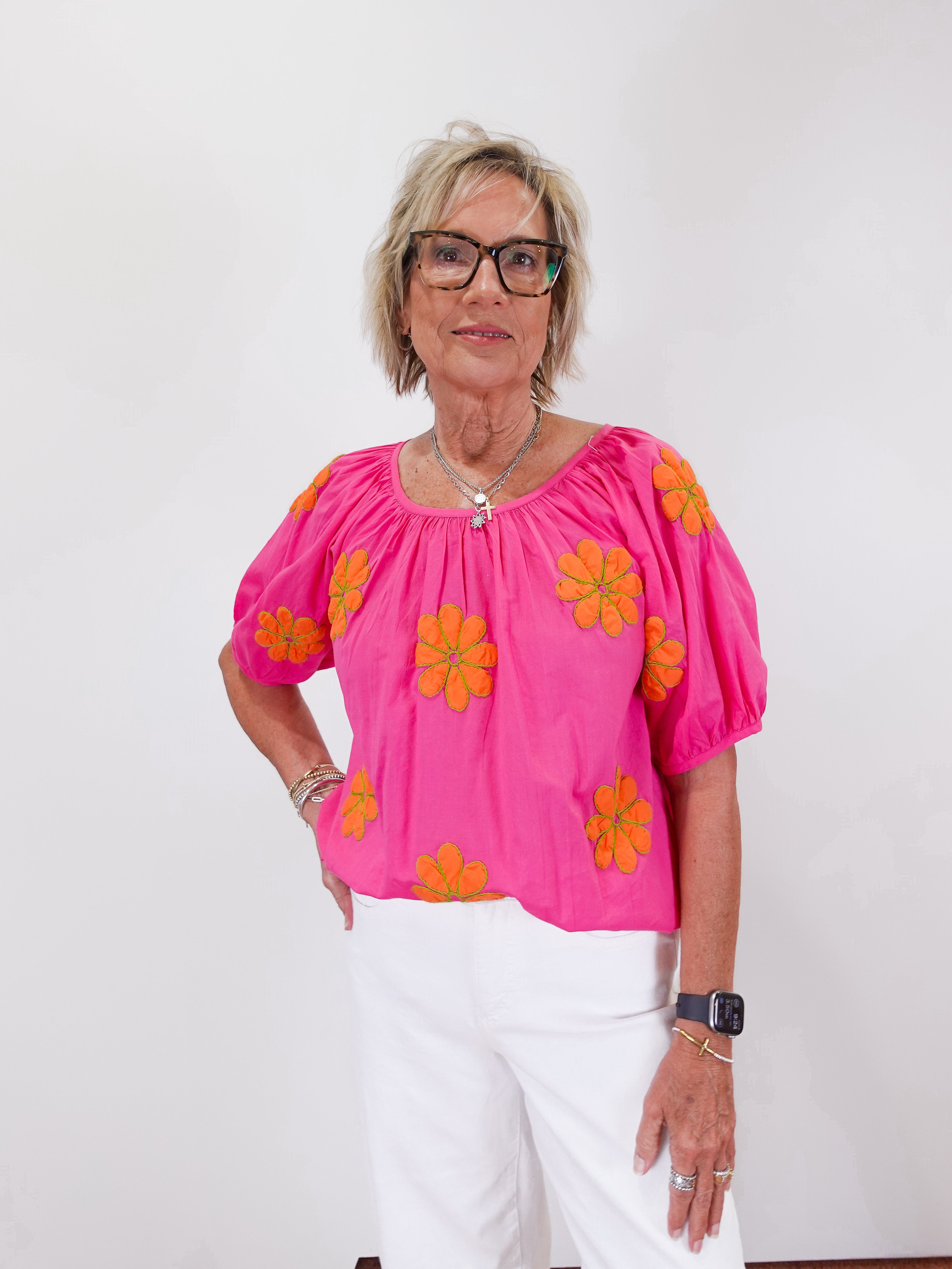 Woman wearing a pink blouse with orange floral patterns on a white background