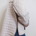 Person wearing a quilted beige jacket against a white background