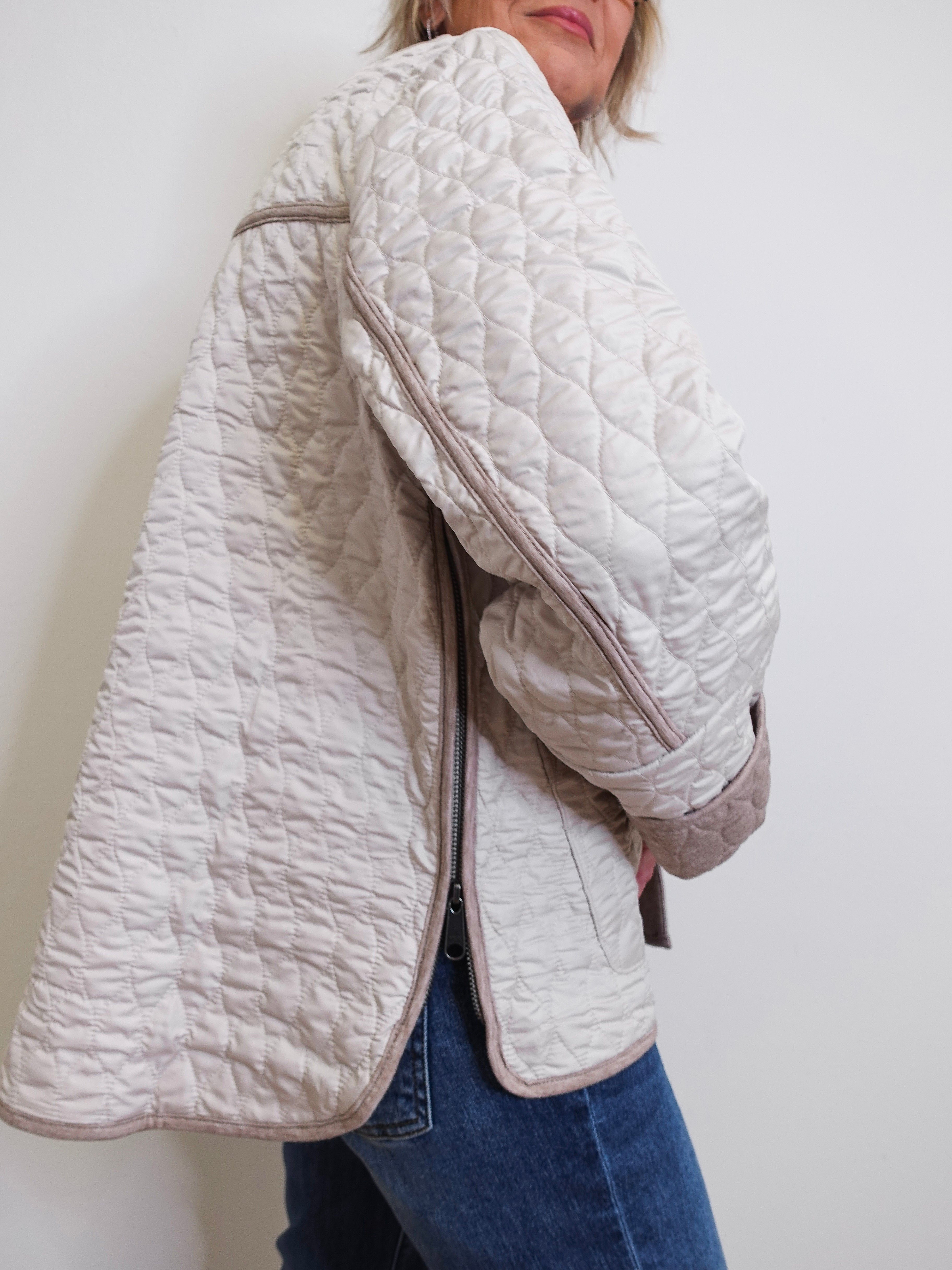 Person wearing a quilted beige jacket against a white background