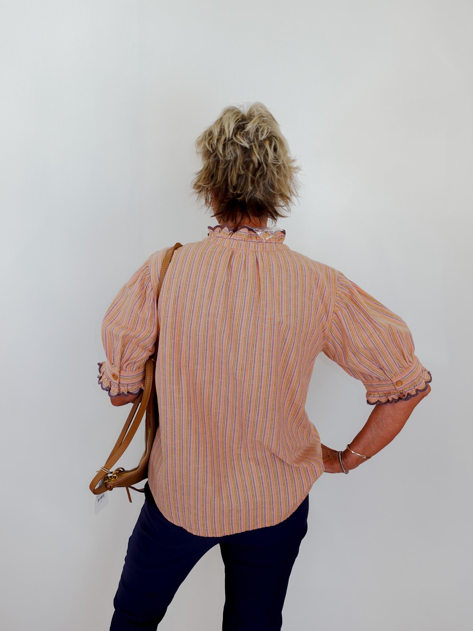 Person wearing a striped shirt and holding a bag against a plain background