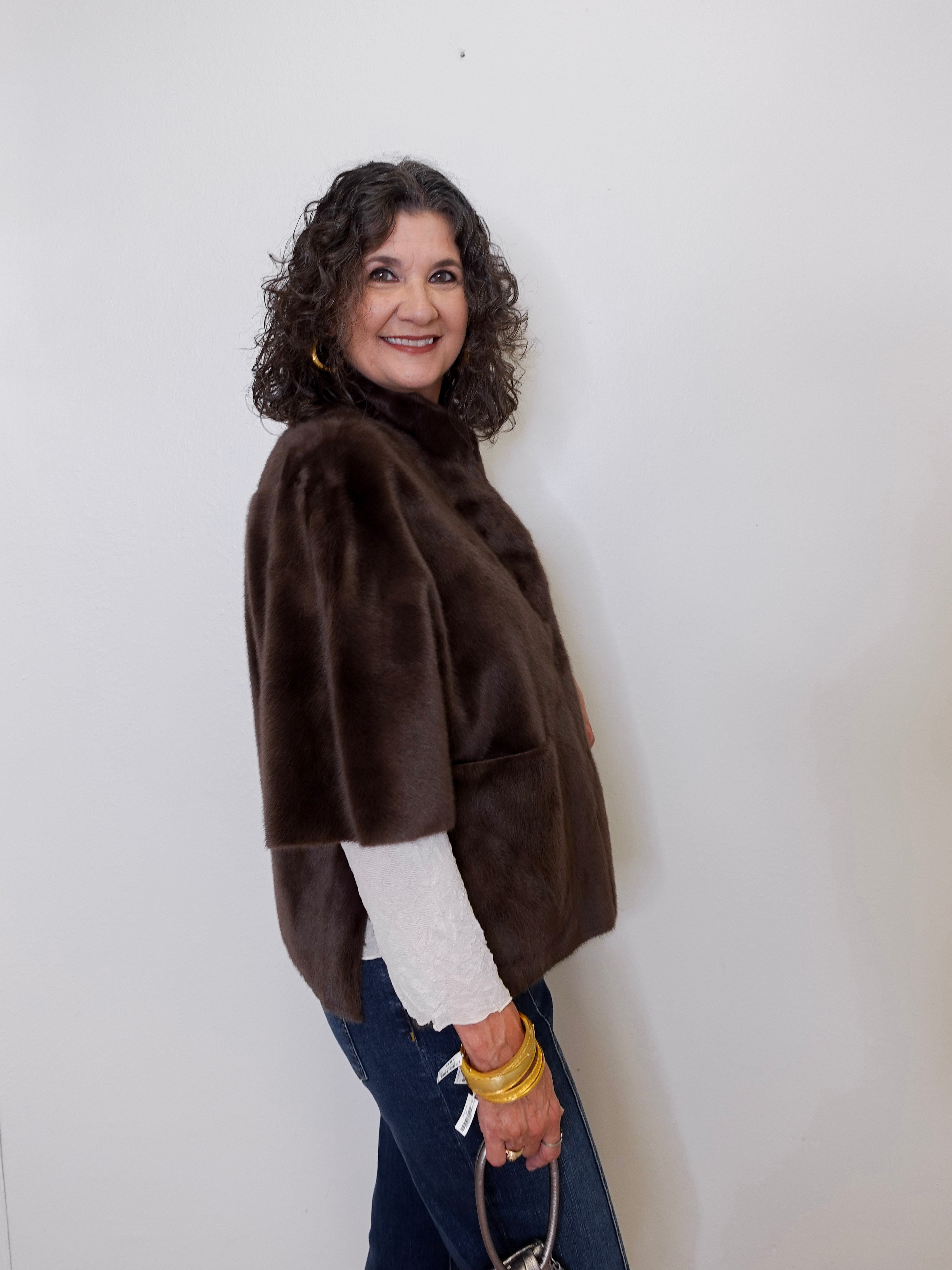 Woman wearing a brown jacket over a white shirt with a plain background