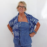 Woman wearing a blue patterned shirt over a denim outfit against a white background