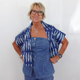 Woman wearing a blue patterned shirt over a denim outfit against a white background