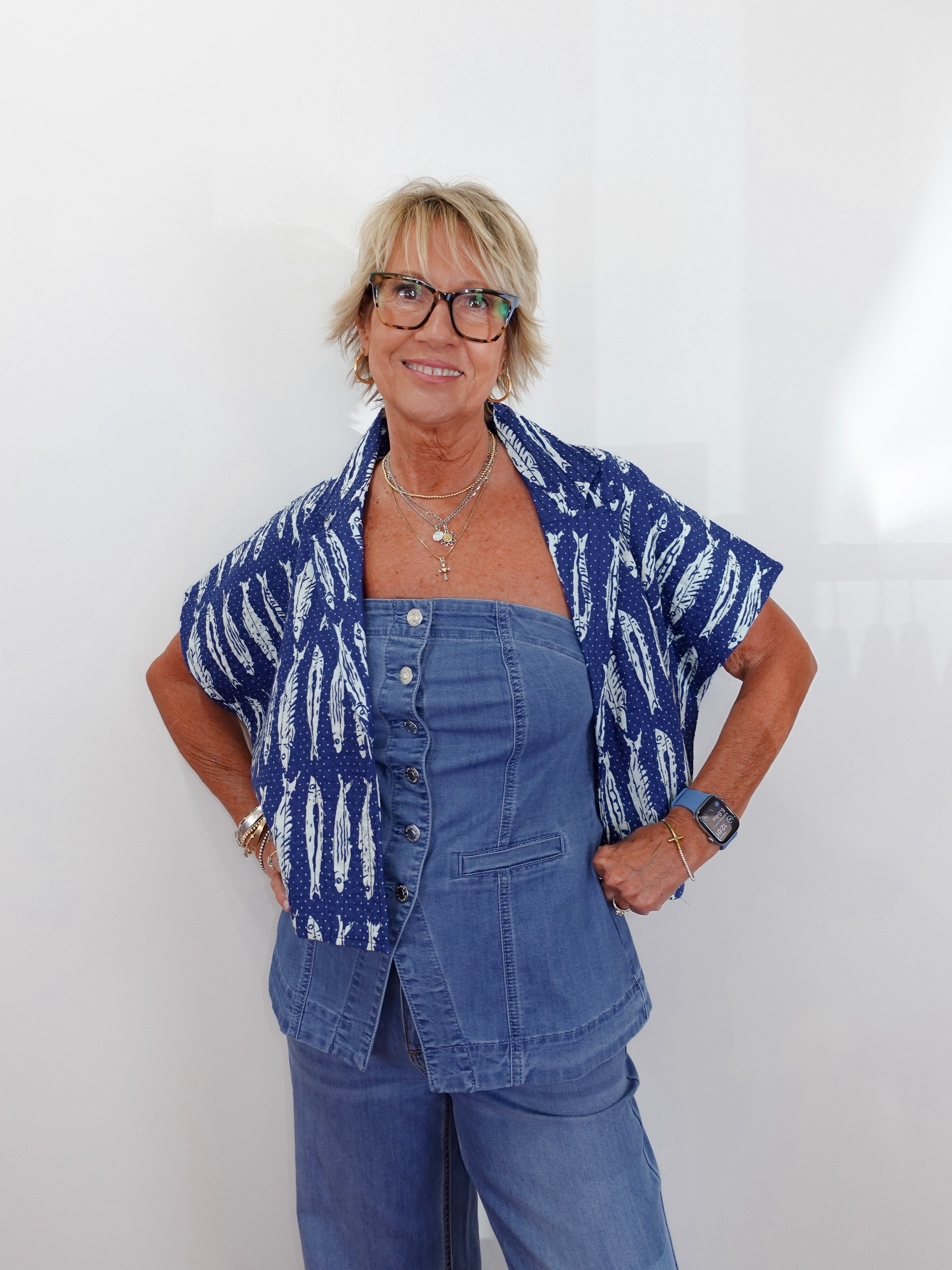Woman wearing a blue patterned shirt over a denim outfit against a white background