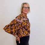 Woman wearing a brown floral blouse against a white background