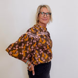 Woman wearing a brown floral blouse against a white background