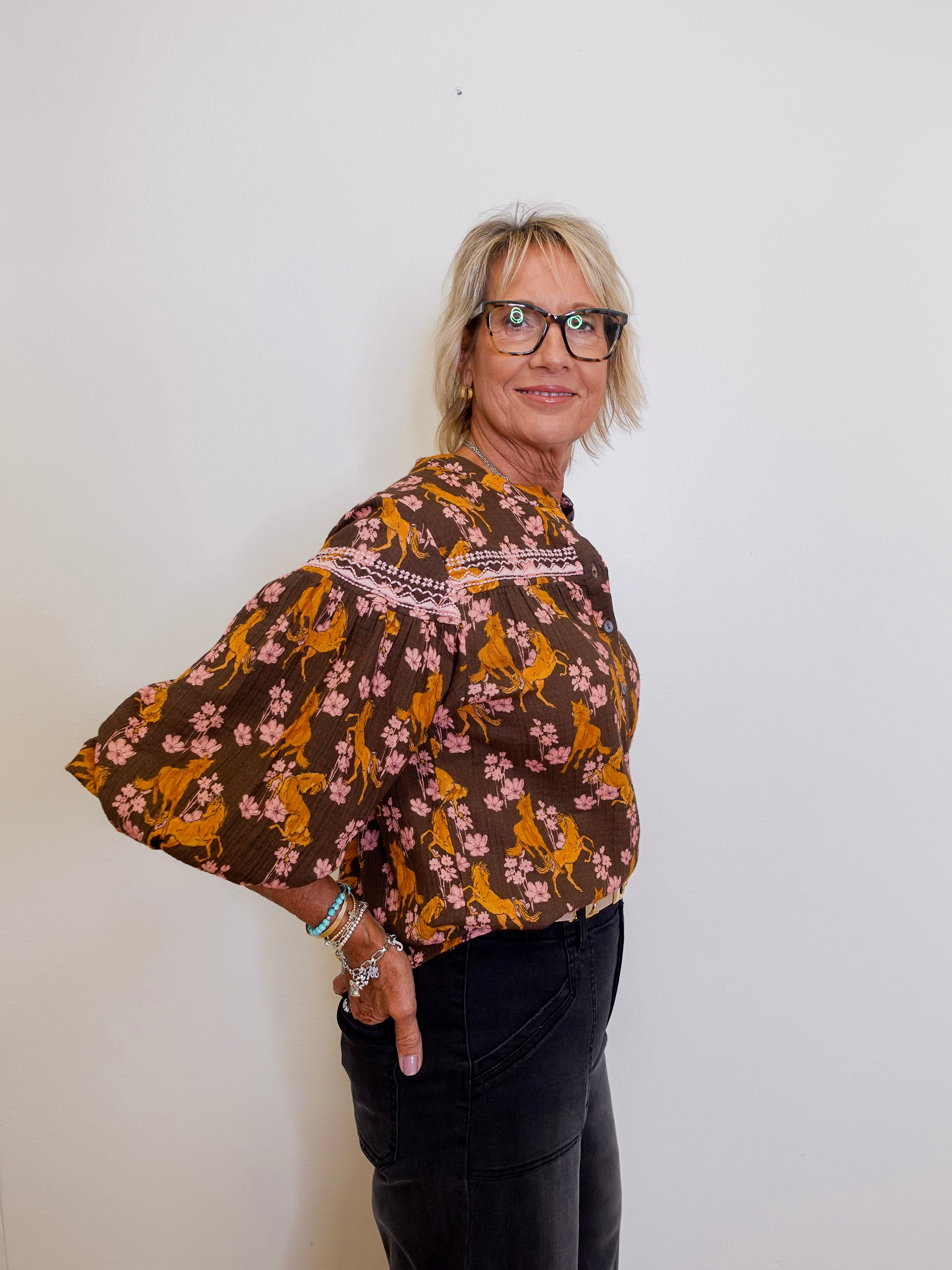 Woman wearing a brown floral blouse against a white background