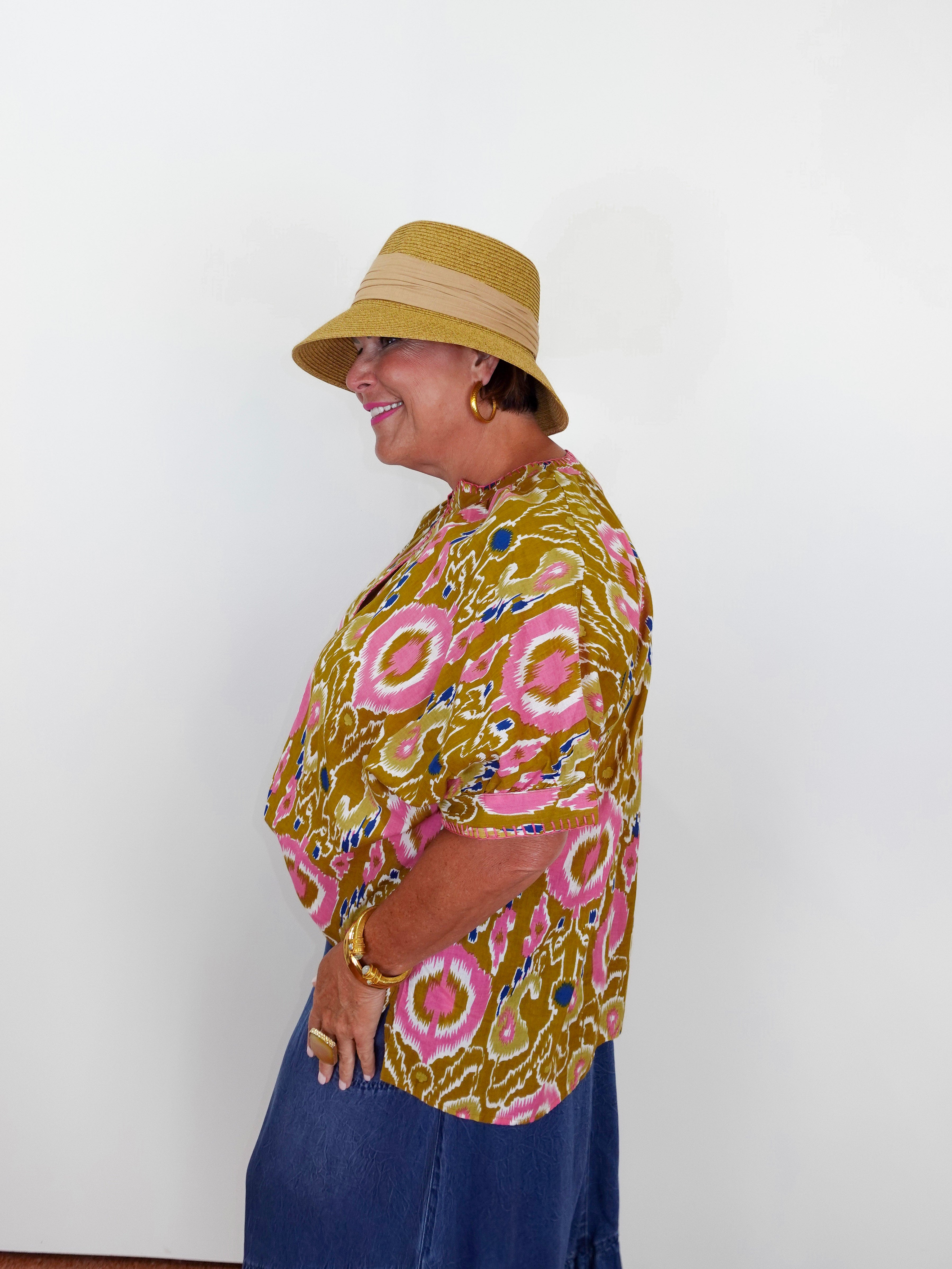 Woman wearing a patterned shirt and hat against a white background