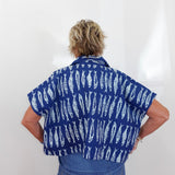 Person wearing a blue shirt with white patterns on a plain background