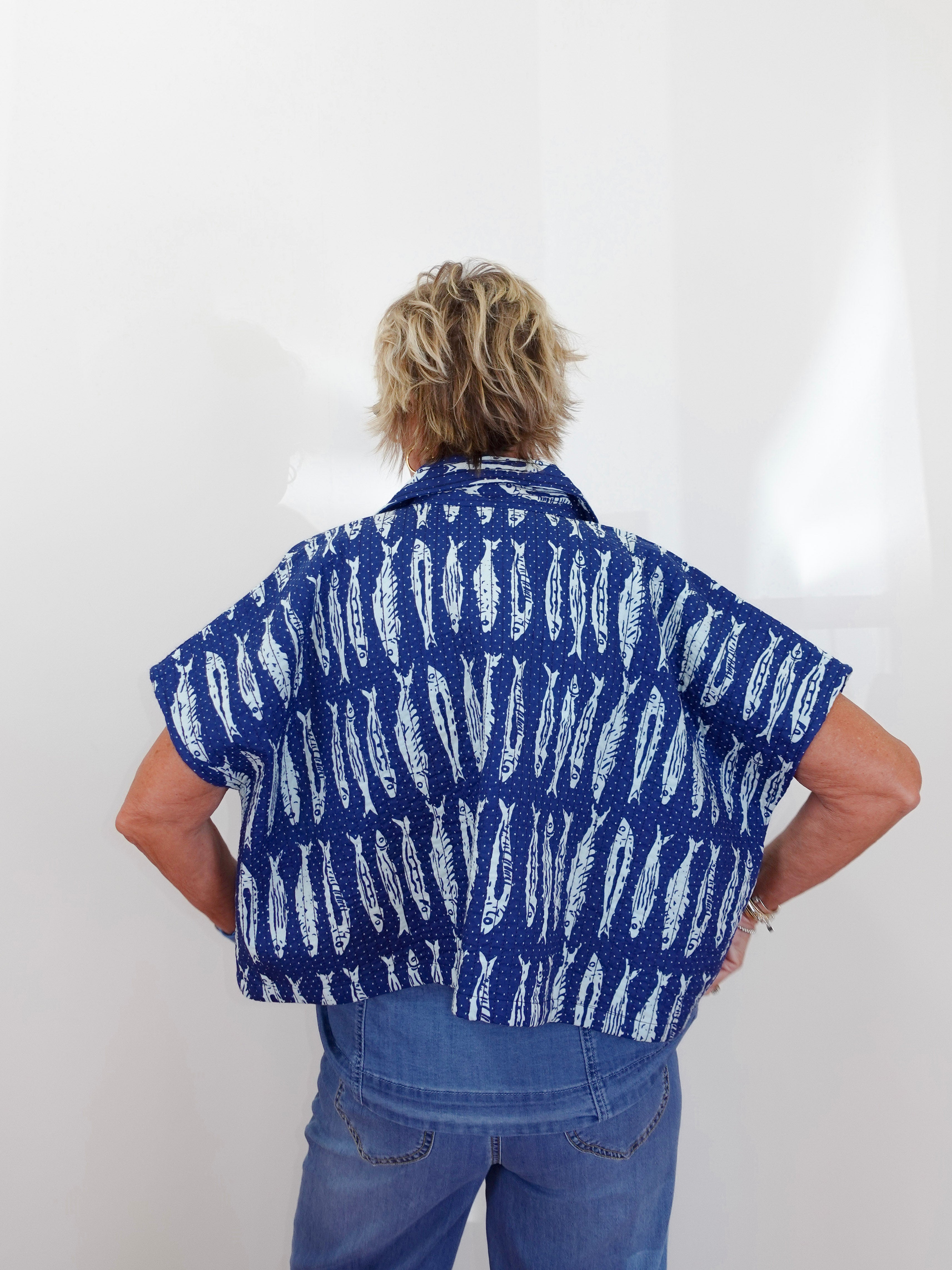 Person wearing a blue shirt with white patterns on a plain background