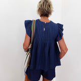 Person wearing a blue dress with ruffled sleeves against a white background
