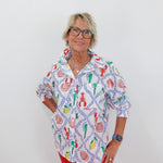 Woman wearing a colorful patterned shirt with red pants on a white background