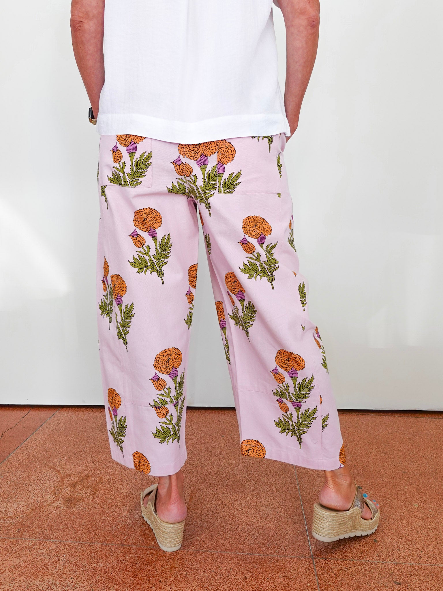 Person wearing light pink floral pants on a plain background