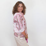 Woman wearing a floral blouse and shorts against a white background