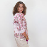 Woman wearing a floral blouse and shorts against a white background
