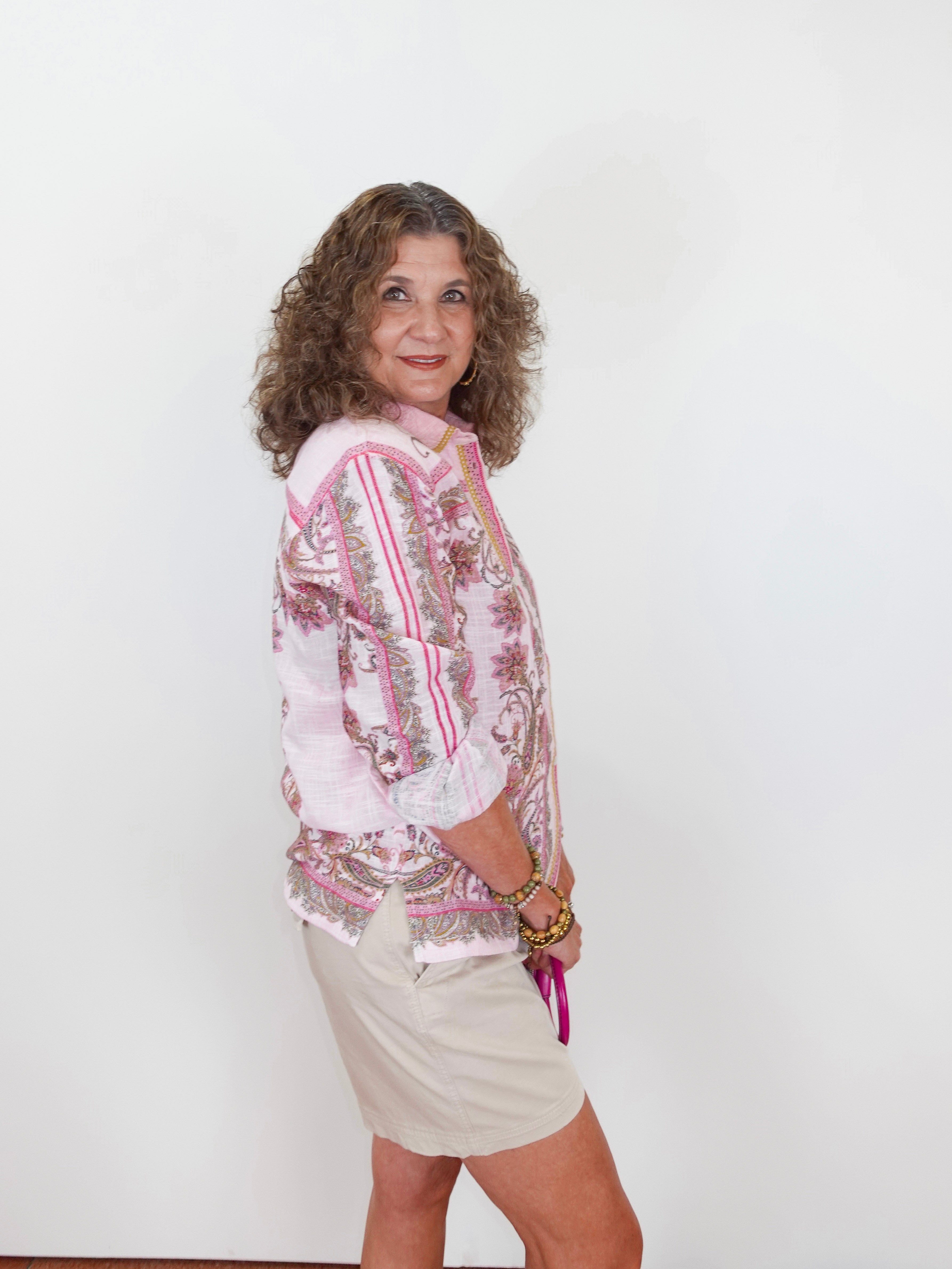 Woman wearing a floral blouse and shorts against a white background