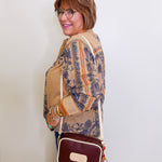 Woman holding a brown handbag against a white wall