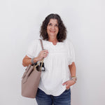 Woman holding a beige handbag against a white background