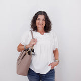 Woman holding a beige handbag against a white background