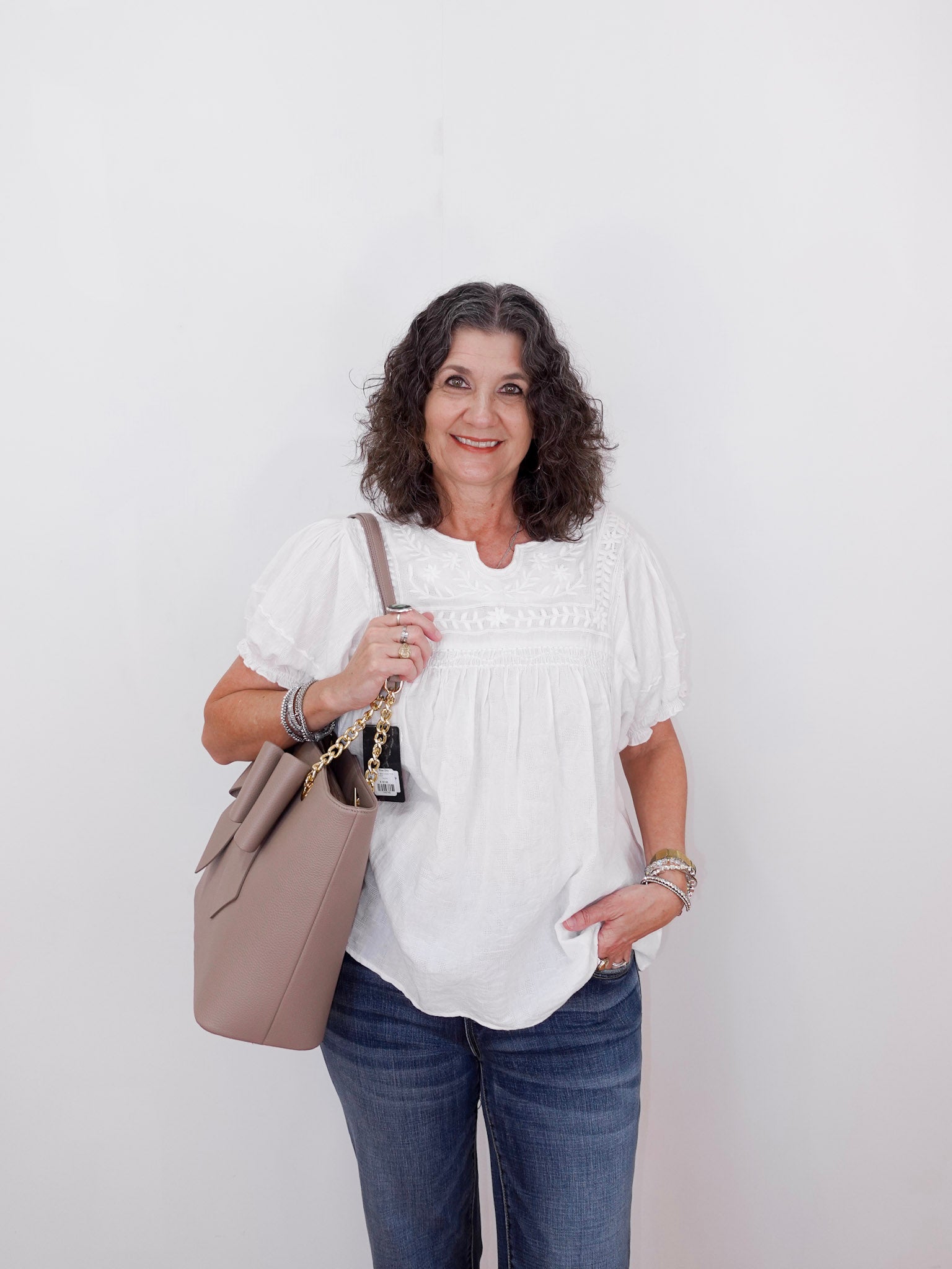 Woman holding a beige handbag against a white background