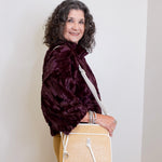 Woman holding a beige handbag against a white wall