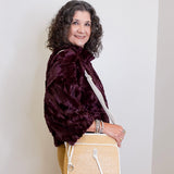 Woman holding a beige handbag against a white wall