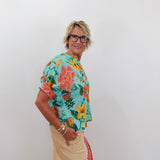 Person wearing a colorful floral shirt and beige pants against a white background