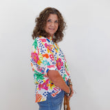 Woman wearing a colorful floral blouse and blue jeans against a white background
