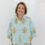Woman wearing a light blue floral-patterned outfit against a white background