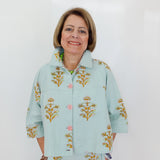 Woman wearing a light blue floral-patterned outfit against a white background